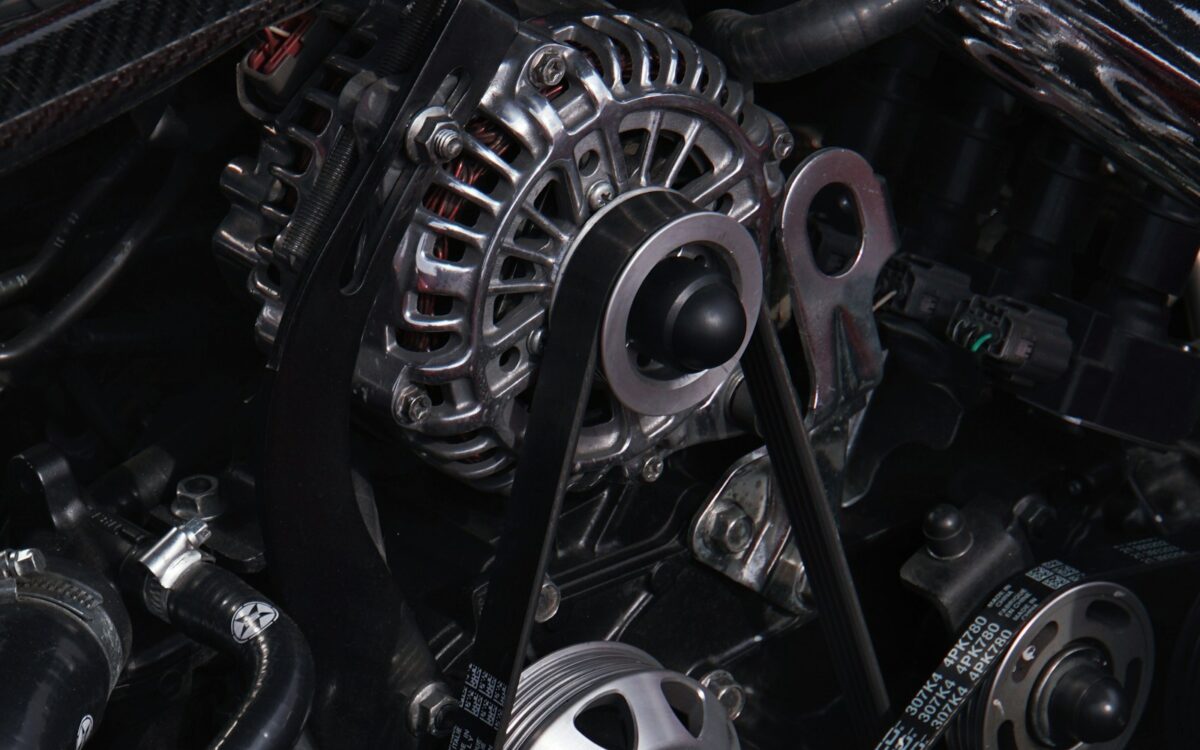 Close-up of a car alternator and serpentine drive belt in an engine bay