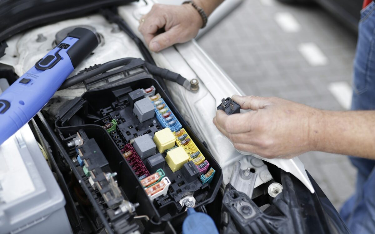 Mechanic testing a car electrical system under the hood