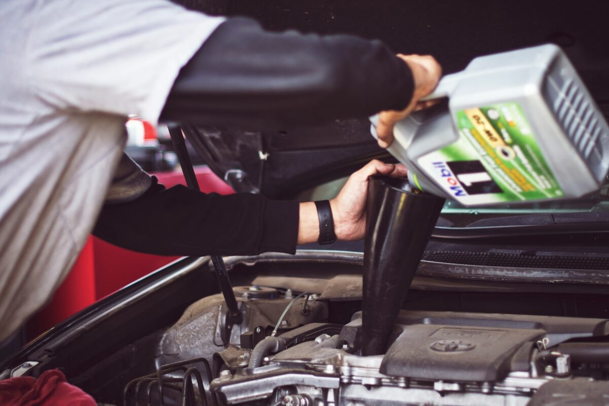 Mechanic pouring fresh motor oil into a car engine during a mobile oil change