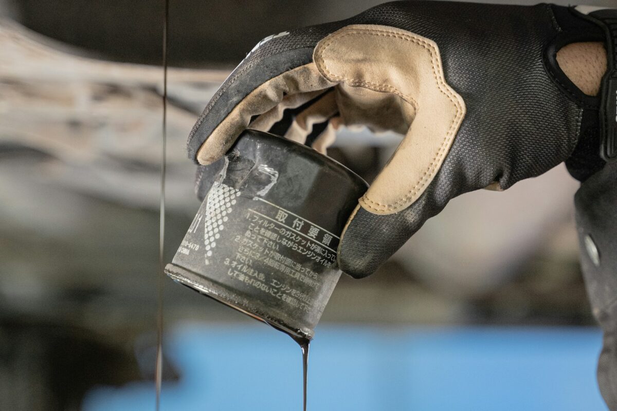 Used oil filter being removed and drained under a vehicle during routine maintenance